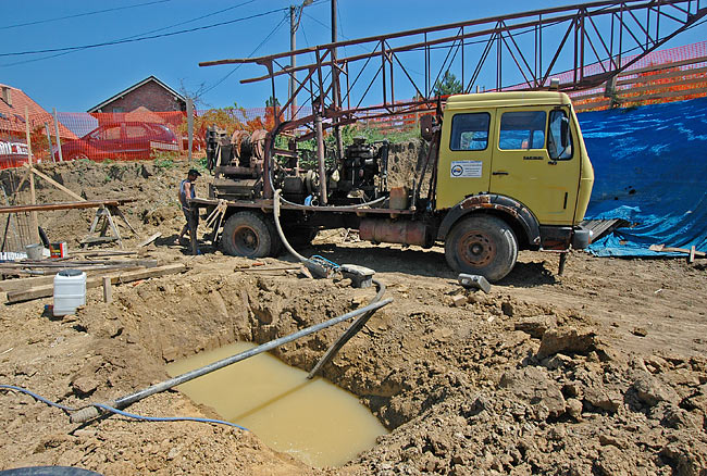 Mud pool filled with water and drilling rig on the back