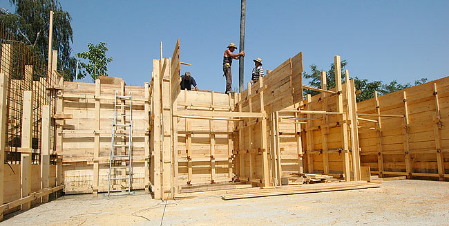 View of the wooden cast filled from the top by 2 workers